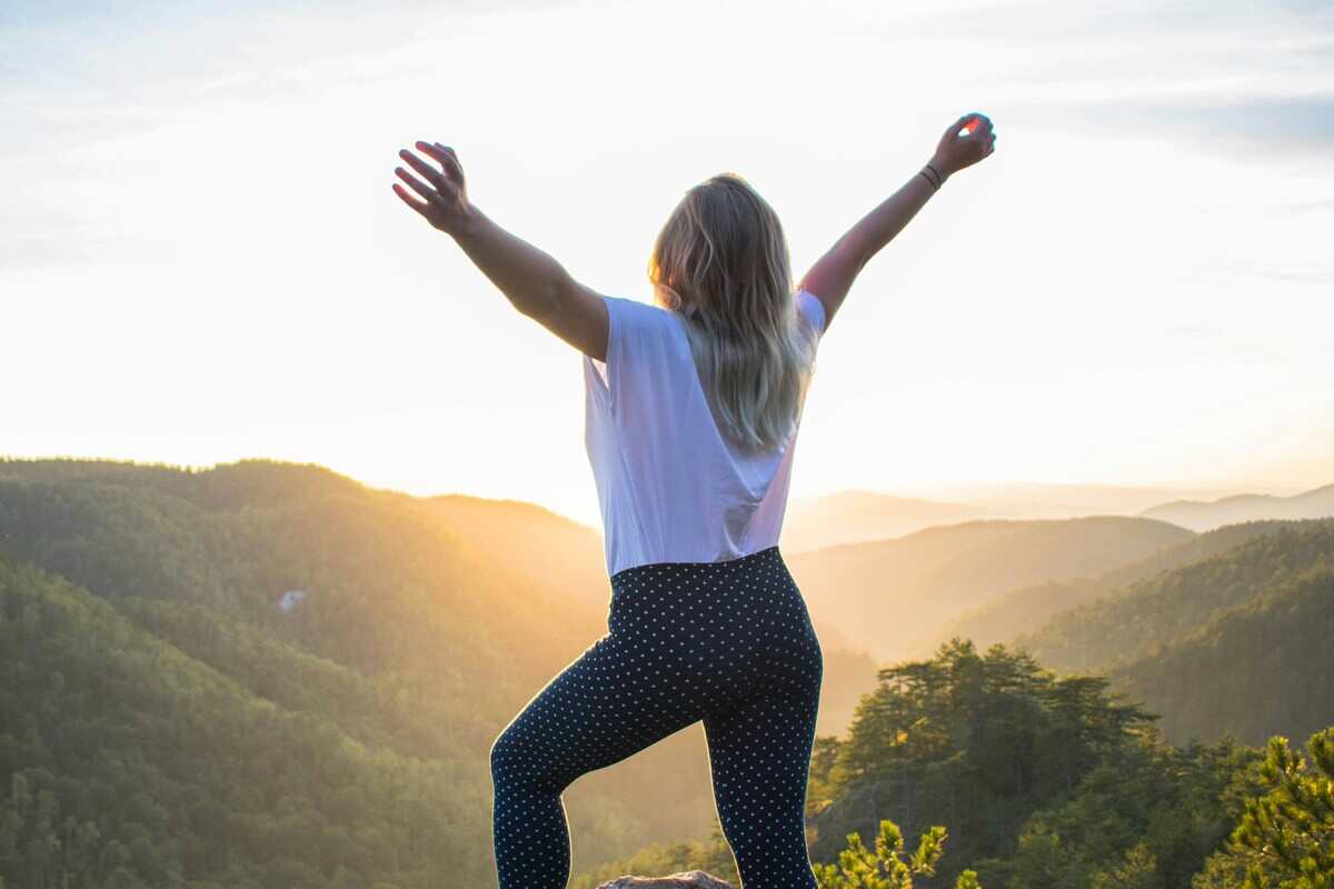 donna felice con braccia alzate in montagna